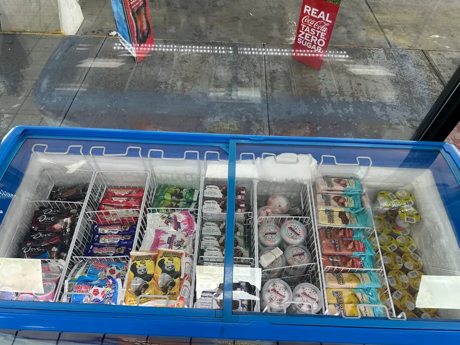 Blue chest freezer stocked with cups and ice cream pops
